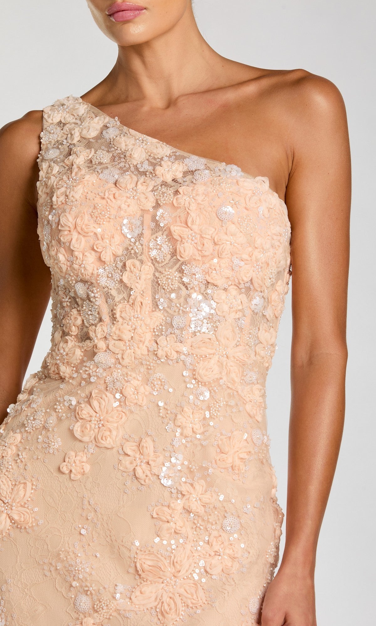 Woman wearing the Mac Duggal 69052 long formal dress in peach, featuring floral appliqué and sequin embellishments, shown from shoulders to hips.